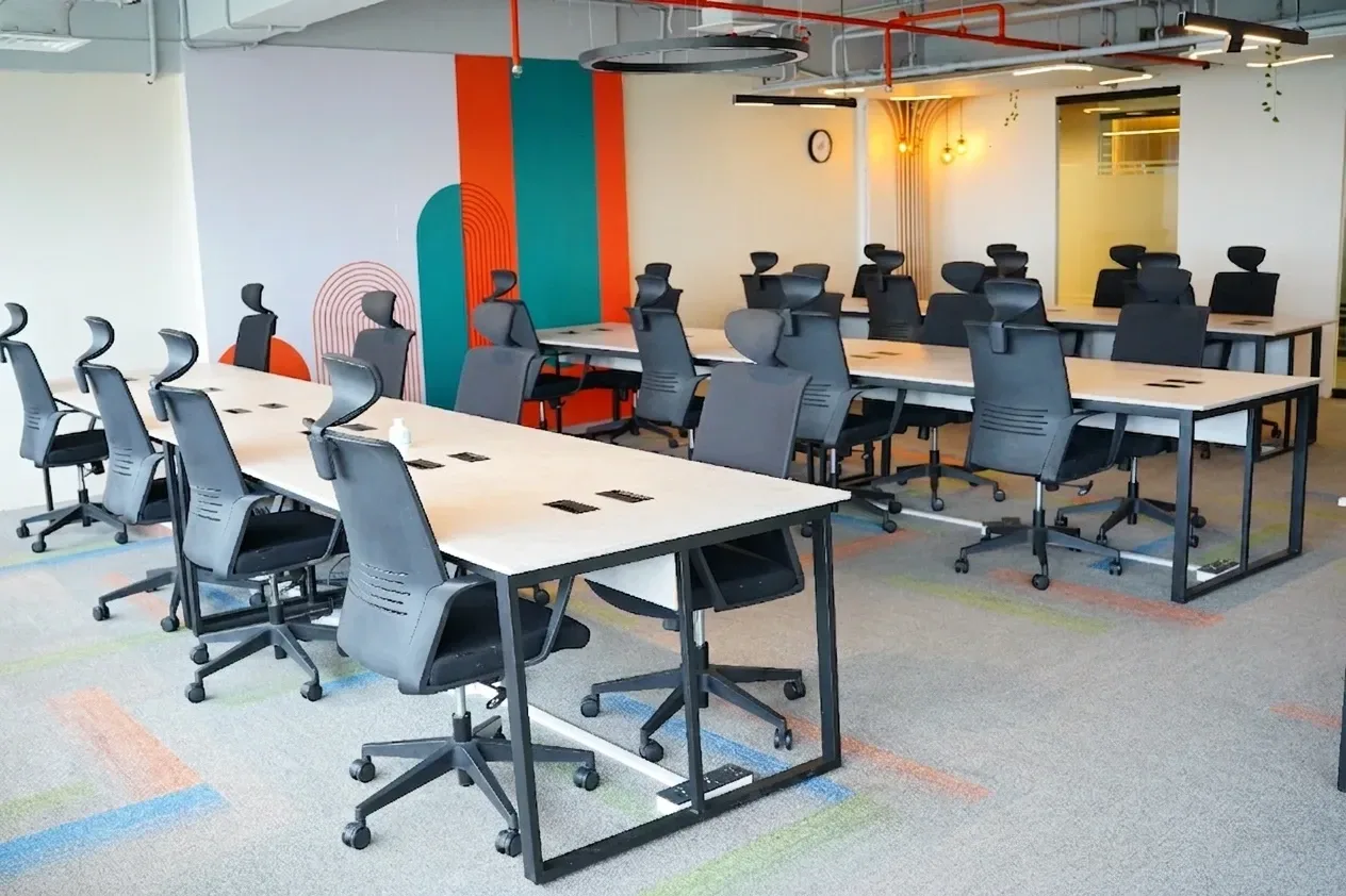 Bahria Town Tower: rows of hot desks with high-backed chairs in front of a painted wall
