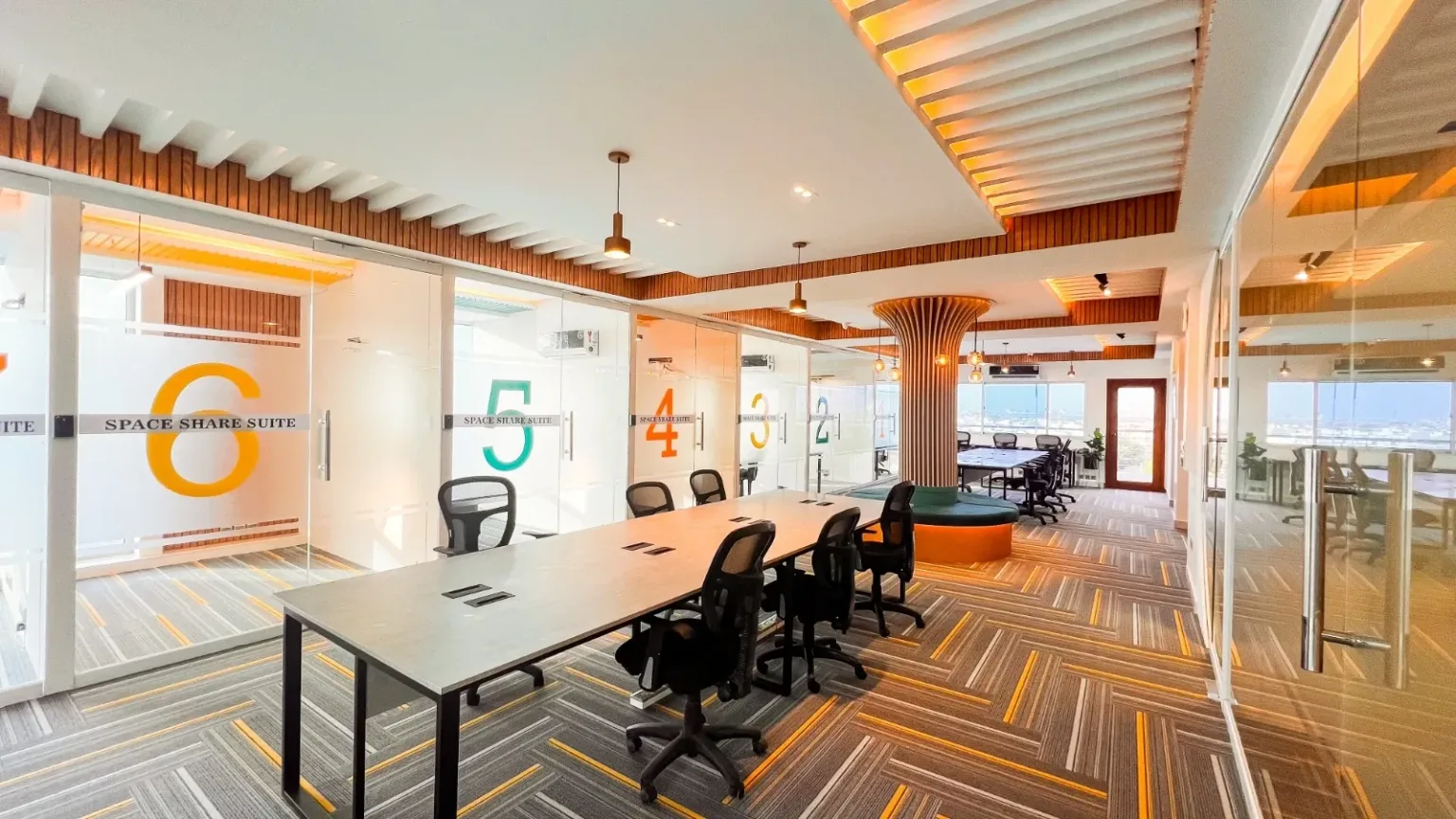 The DHA Phase 6 floor: a long shared table beside the numbered glass suites